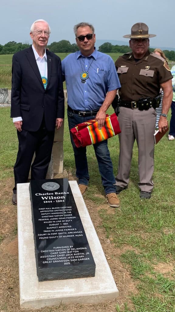 Three people stand next to a monument.