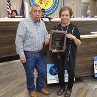Two people pose for a photo holding a plaque.