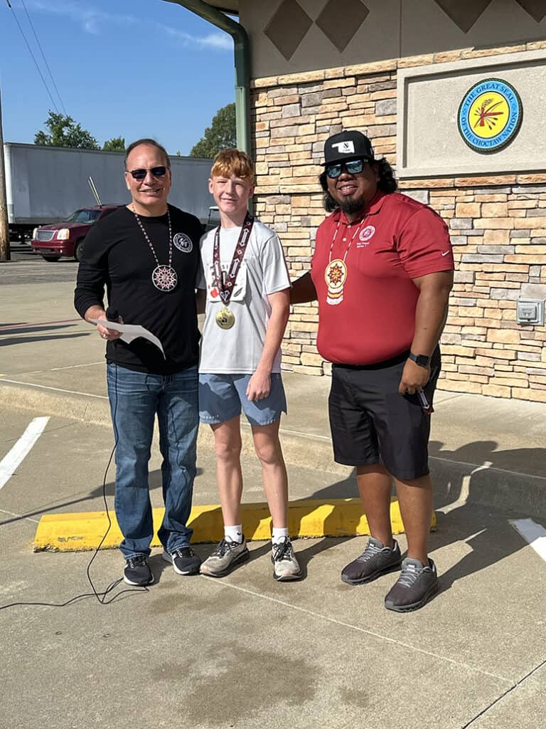 Young man stands between Chief Gary Batton and Councilmember Joey Tom.