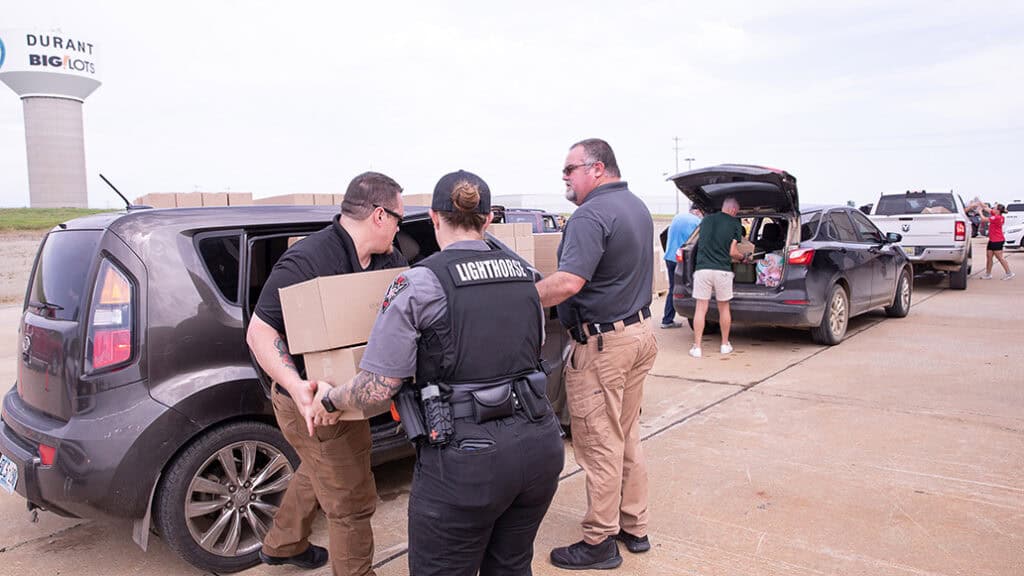 Men and women load packages into a car.