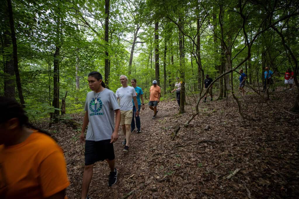 a group of people hike through the woods.