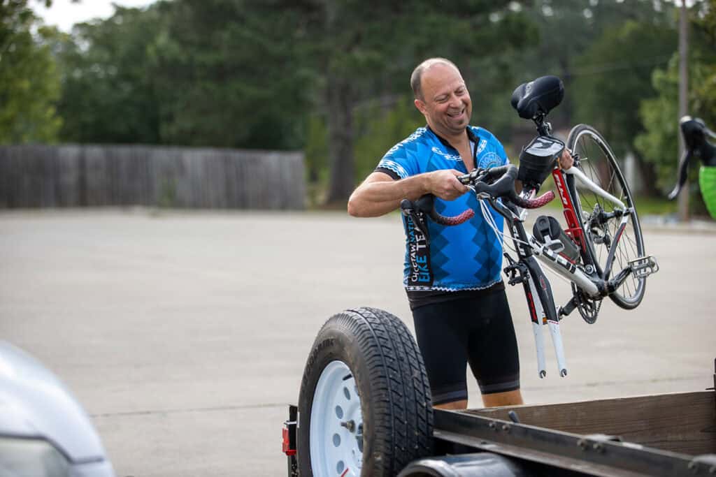 A man loads a bicycle onto a trailer.