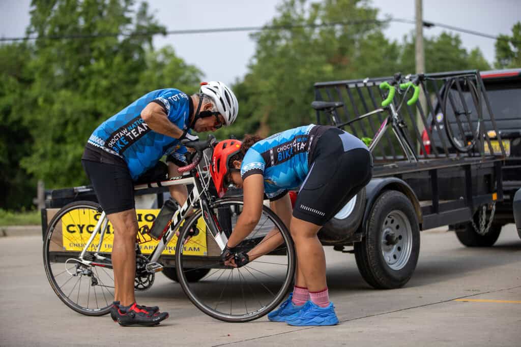 A man holds a bicycle as a woman takes the front wheel off.