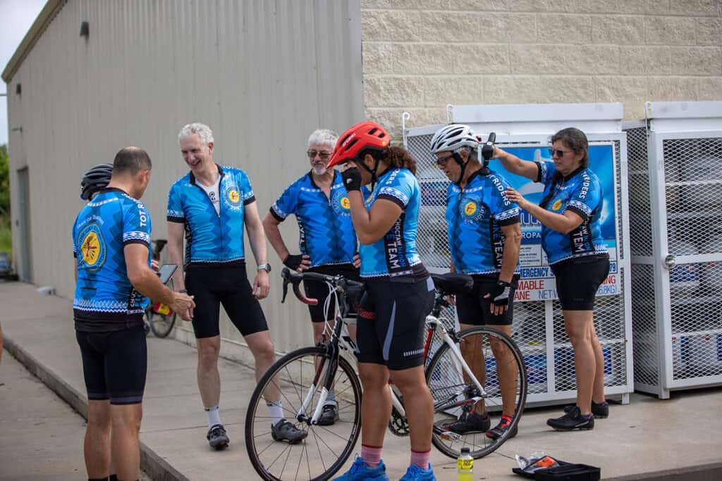 A group of cyclists gather outside.