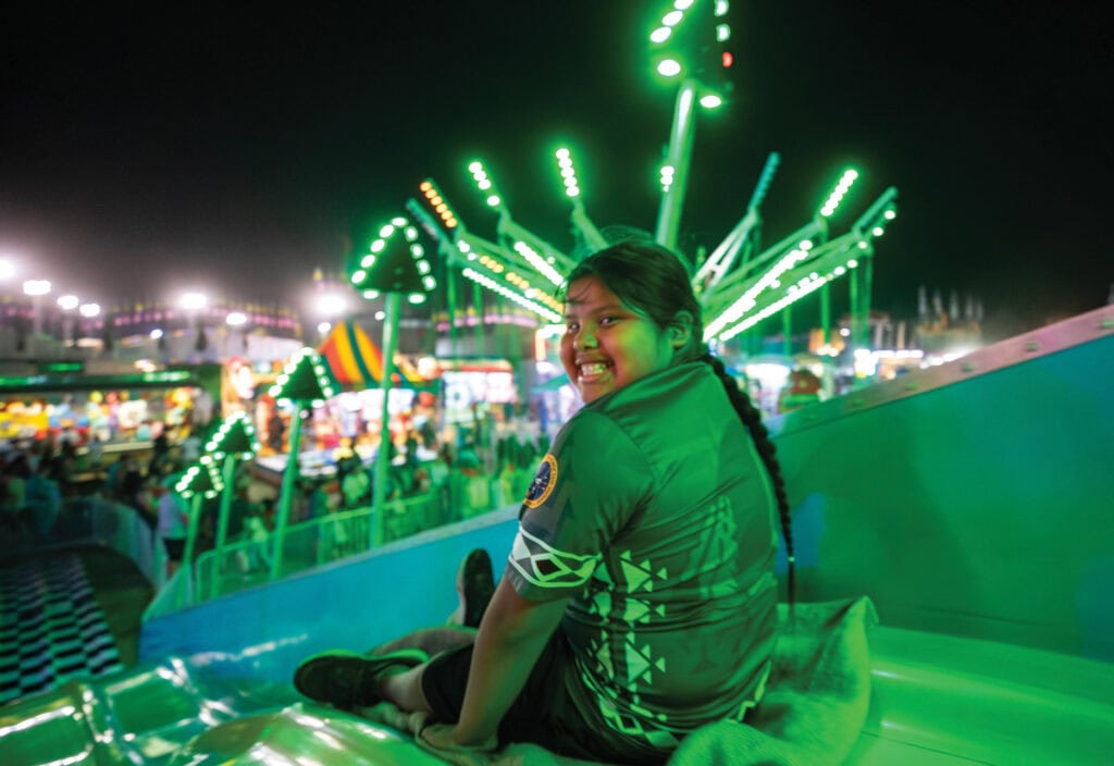 A young boy smiles at the camera before going down a carnival slide.