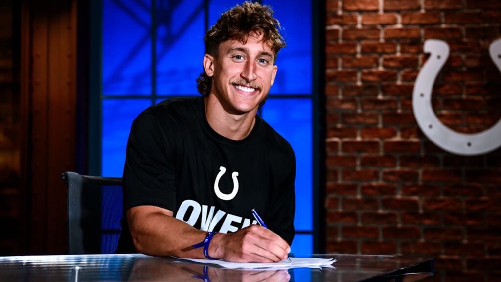 A man poses for the camera while holding a pen.