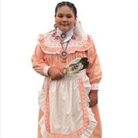 Young girl stands, holding a feather, wearing a peach colored traditional dress.