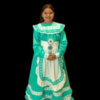 Young girl stands, smiling, wearing a turquoise and white traditional dress.