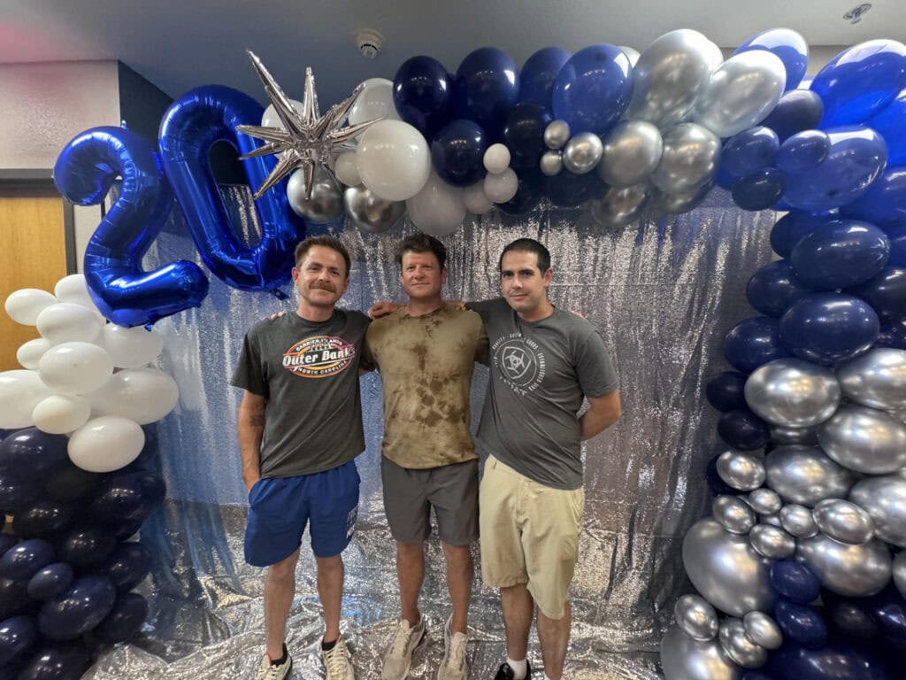 Three men pose for a photo.