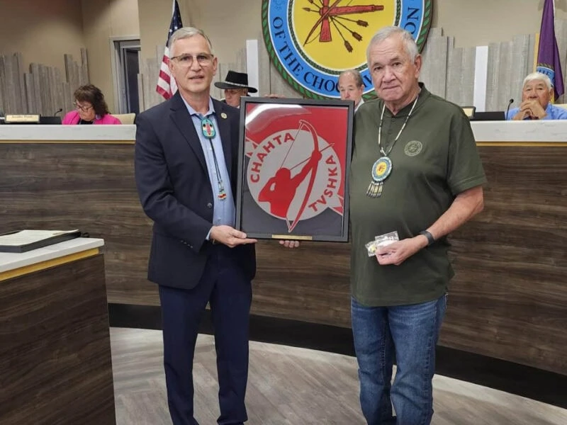 Two men pose with an award.