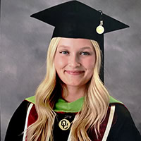 A woman poses for the camera wearing a graduation robe.