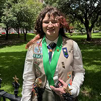 A young woman poses for the camera wearing a Girl Scout uniform.