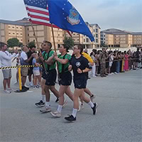three people run carrying flags.