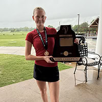 A young girl poses for the camera holding a large trophy.