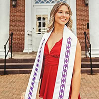 A woman poses for the camera wearing a Choctaw graduation stole.