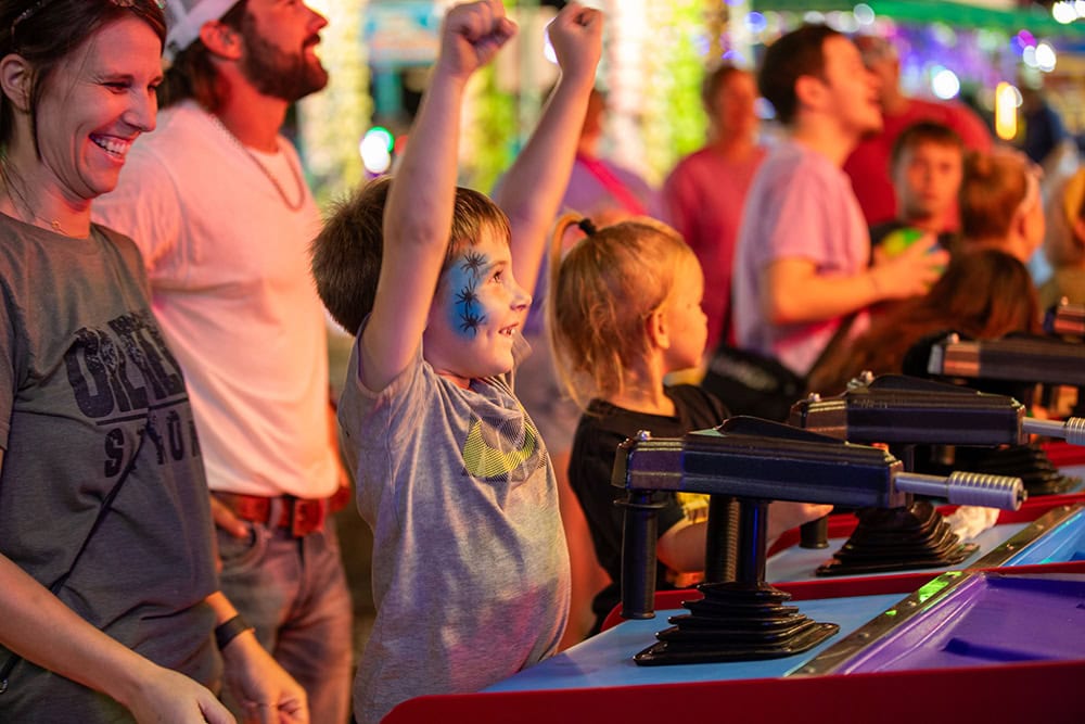 A boy celebrates at a carnival game.