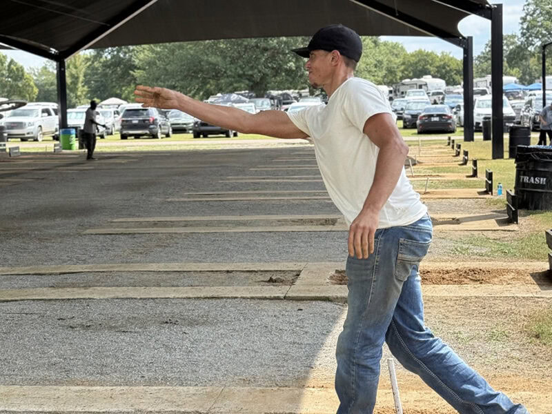 A man tosses a horseshoe.