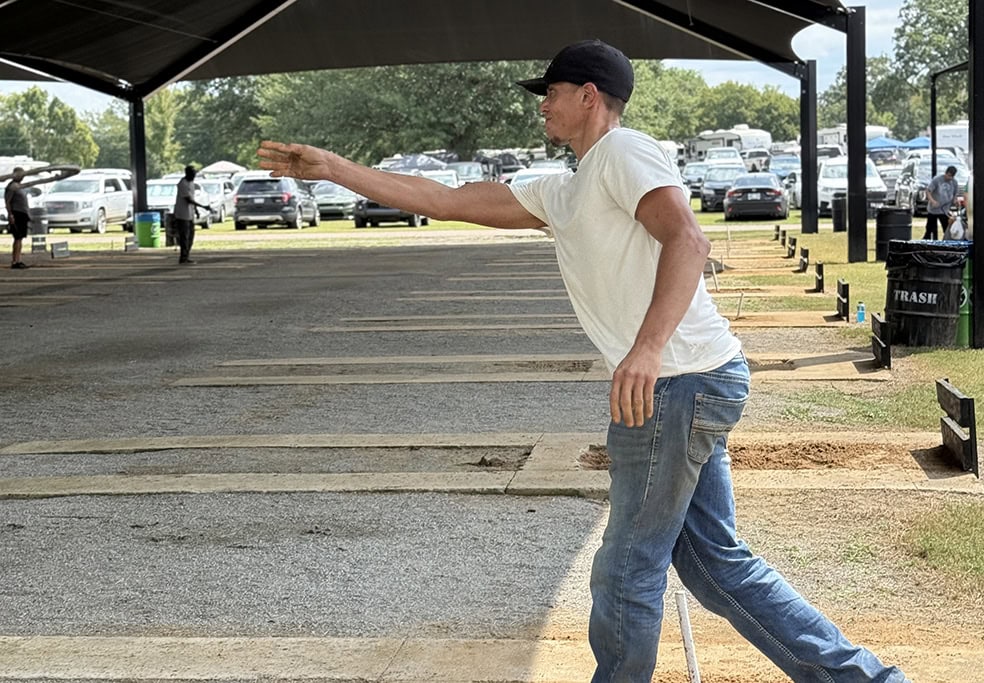 A man tosses a horseshoe.