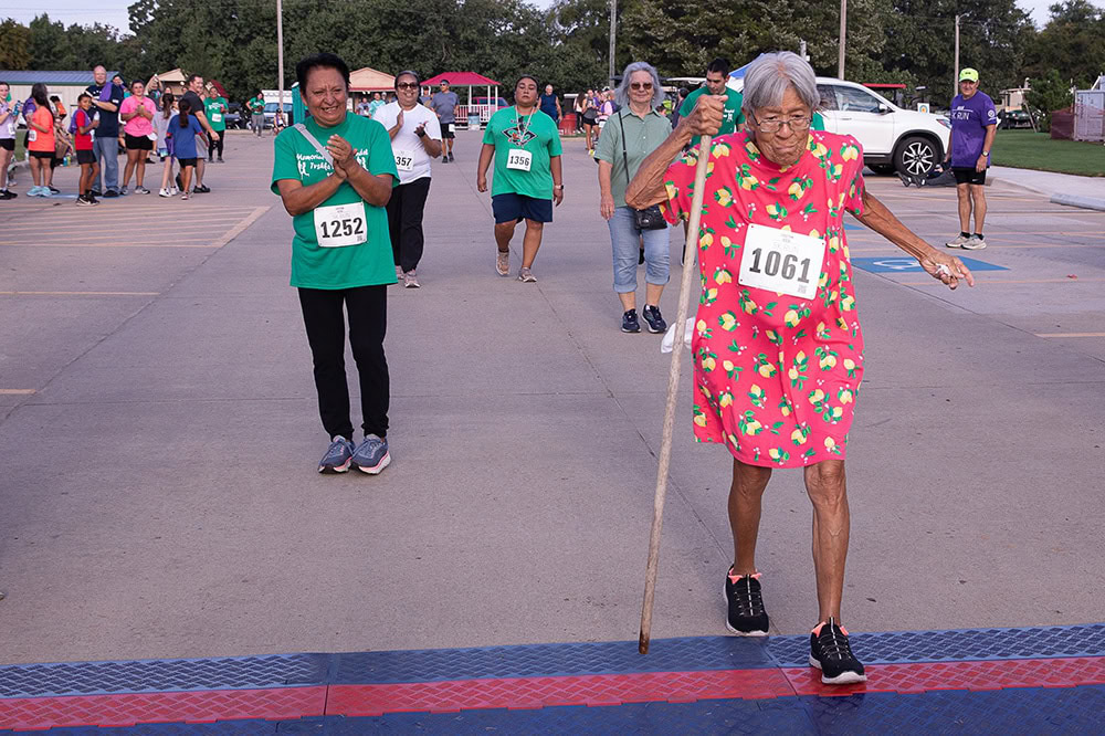 An elderly woman crosses the finish line.