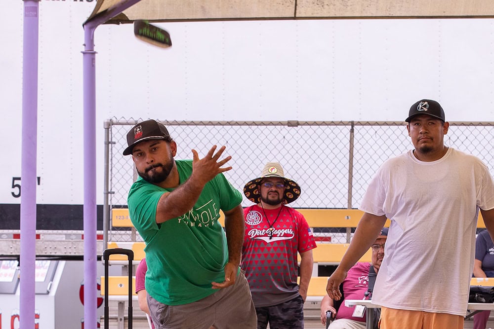 A man throws a cornhole bag.