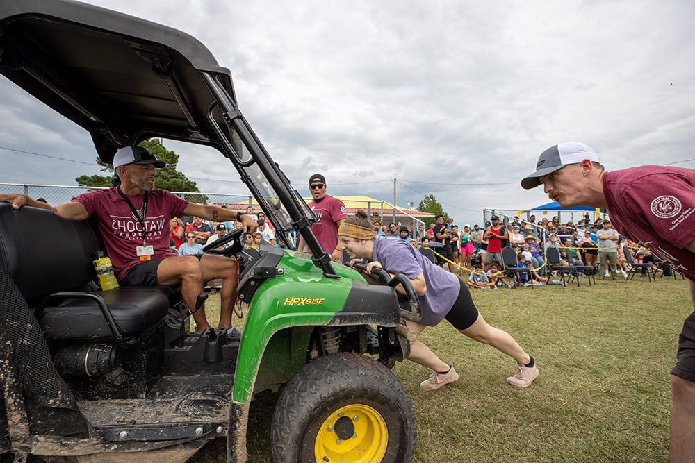 A woman pushes a utility vehicle.
