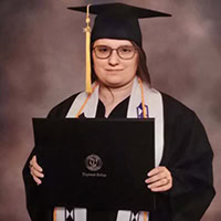 Young woman holds up diploma.