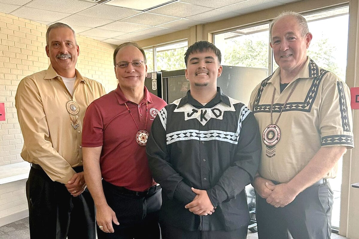 A young man stands with tribal leadership