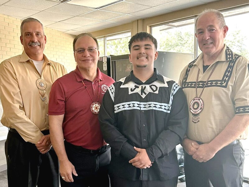 A young man stands with tribal leadership