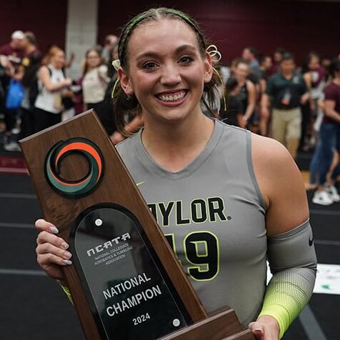 A young woman holds a trophy and smiles.