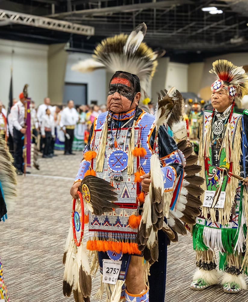 A man wears Native American regalia.
