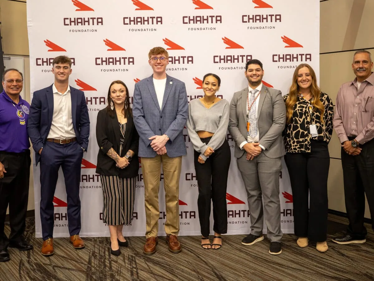 A grtoup of young men and women pose for a photo with tribal leadership.