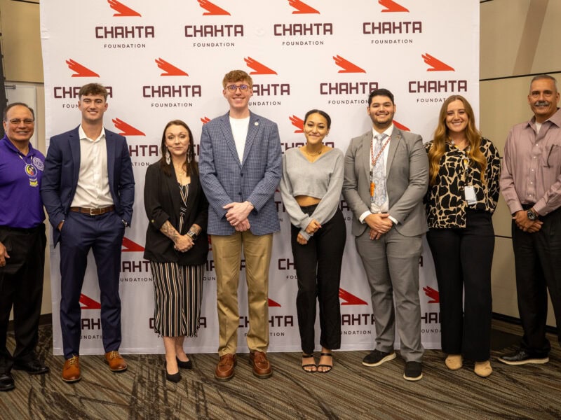 A grtoup of young men and women pose for a photo with tribal leadership.