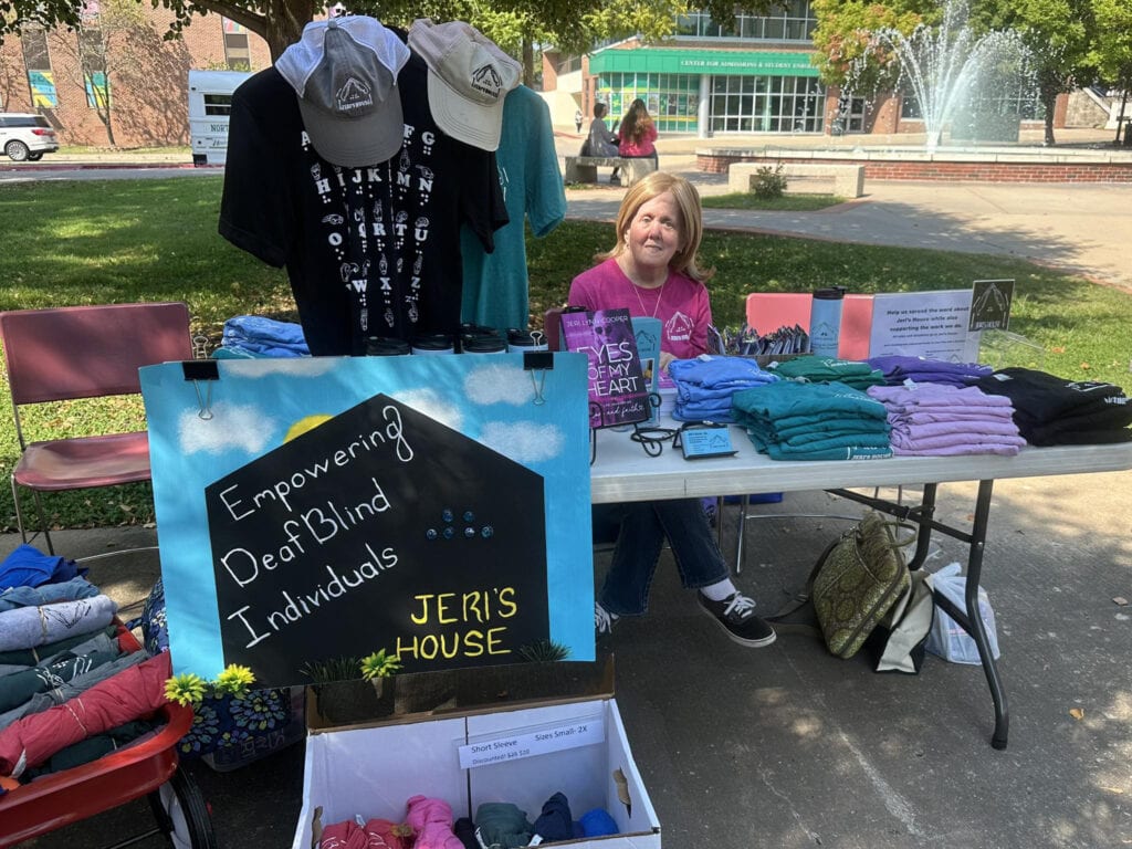 A women sits at a table with items for sale.