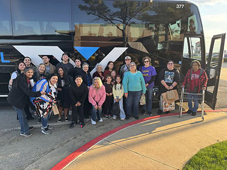 A group of people pose for a photo in front of a bus.