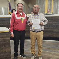 Two man pose for a photo with one holding a certificate.