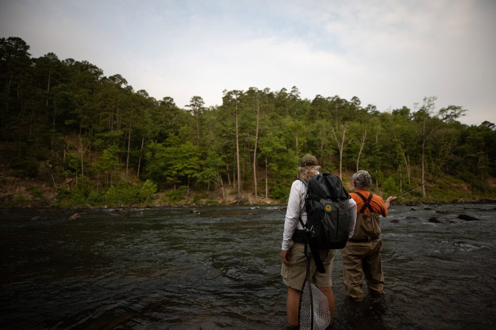 Two men fishing in a river.