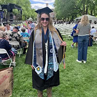 Young woman, dressed in cap and gown, poses for a photo.