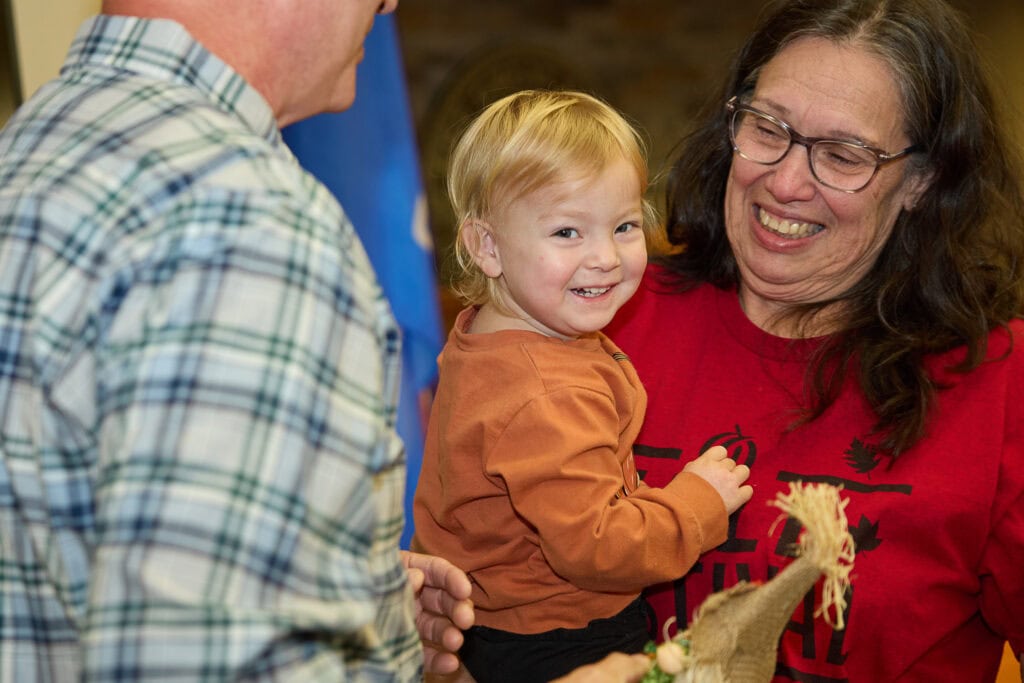 Young boy smiles for the camera as he is held.