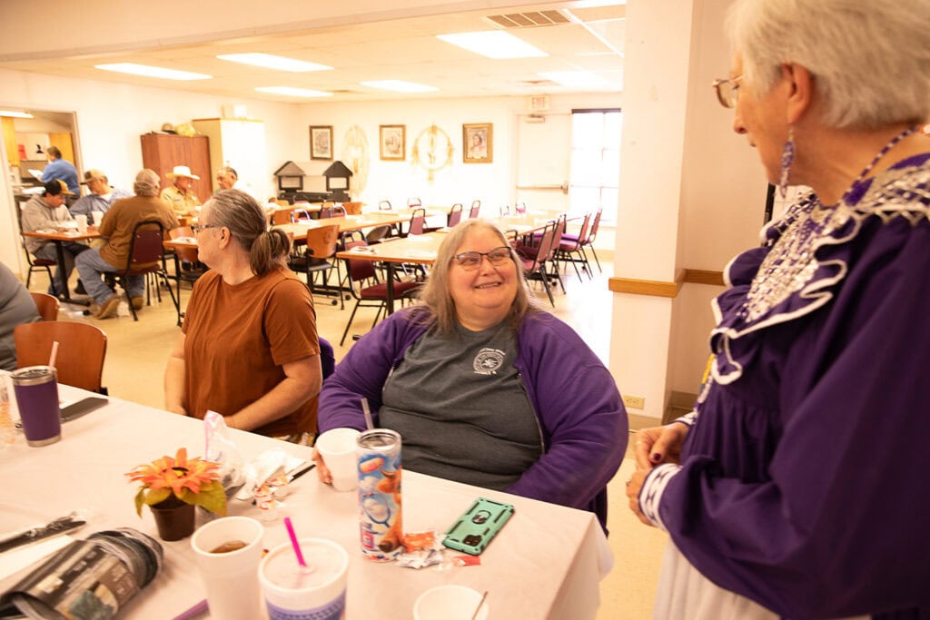 two women talk at a table.