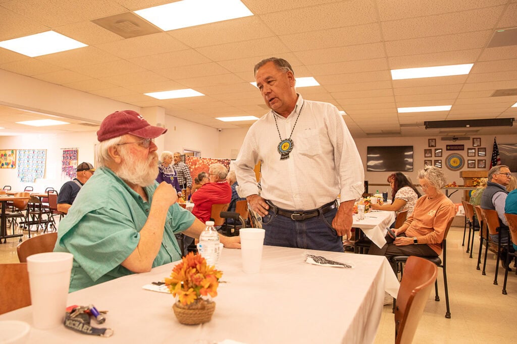 Two men talk at a table.