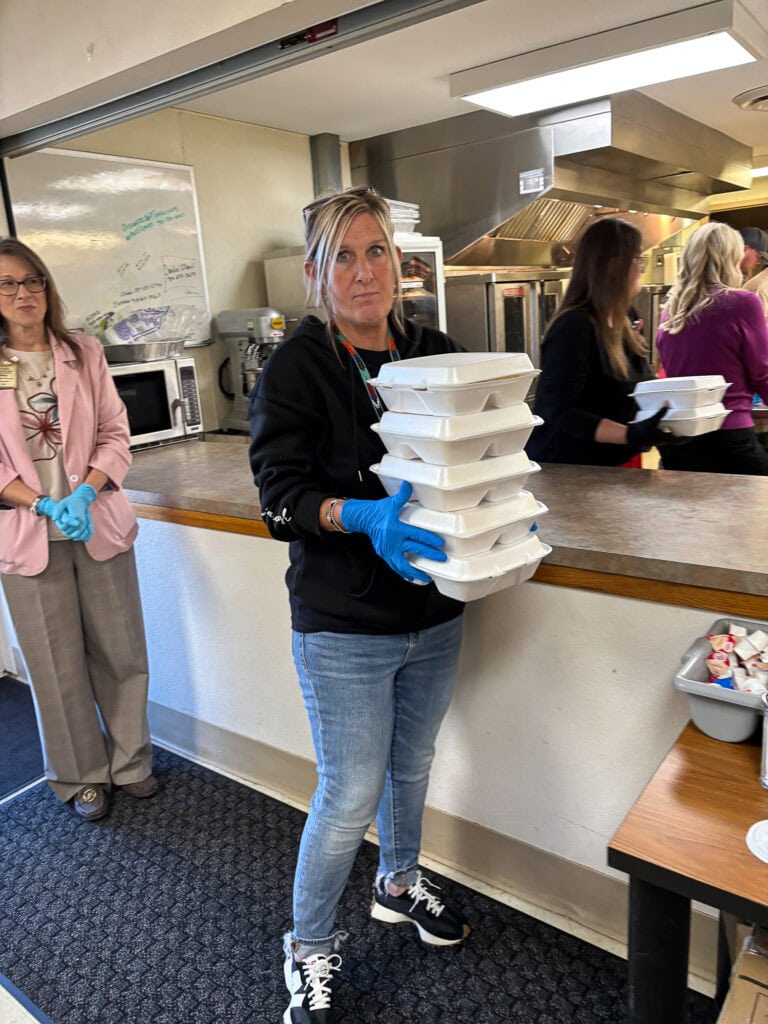 A volunteer holds a stack of to-go boxes.