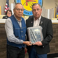 Two man pose for a photo holding an award.