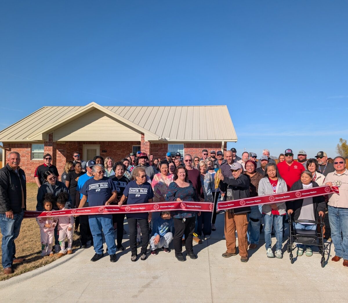 A large group of people cut a grand opening ribbon.