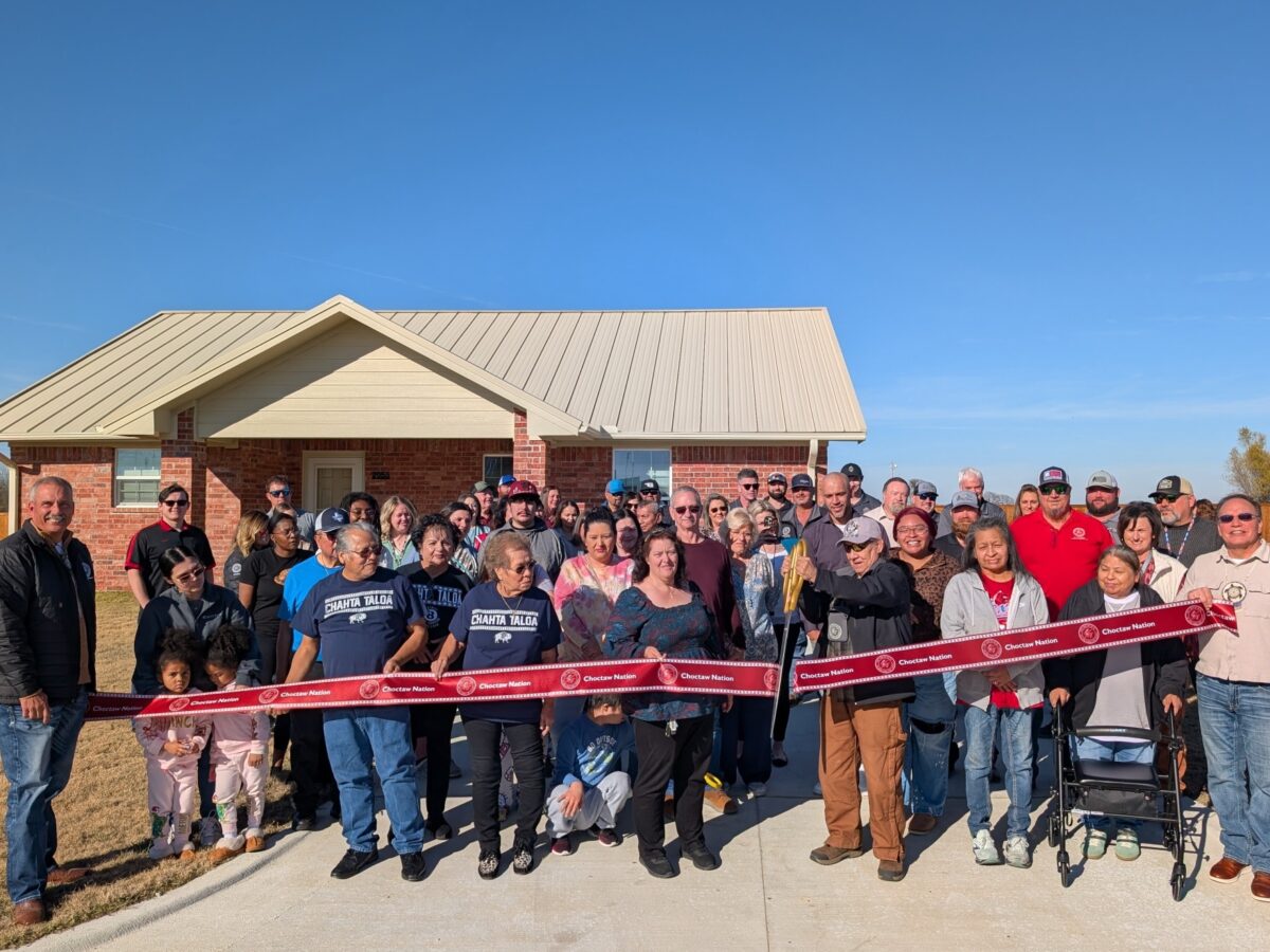 A large group of people cut a grand opening ribbon.