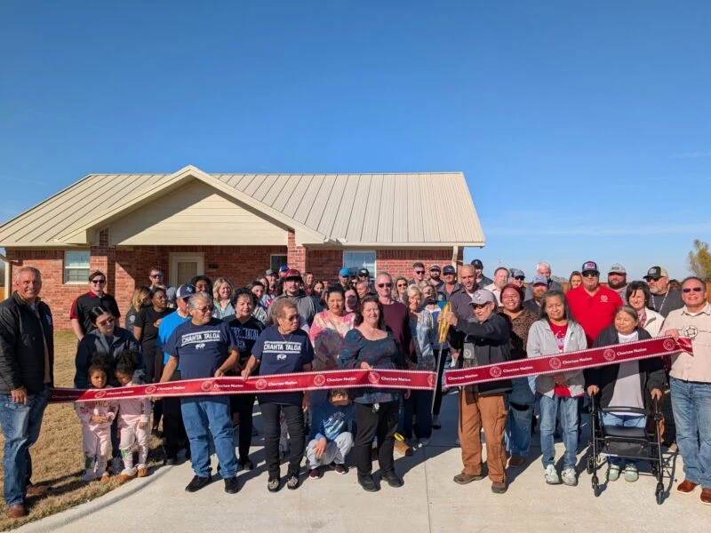 A large group of people cut a grand opening ribbon.