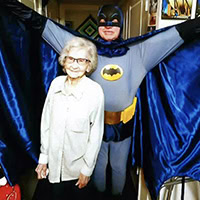 A woman poses for a photo with a man dressed in a Batman costume.