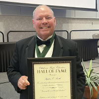A man poses for a photo holding an award.