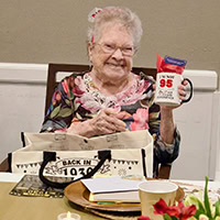 A woman smiles for the camera holding her gifts.