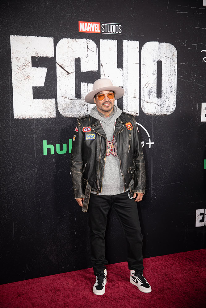 A man stands on the red carpet posing for pictures.