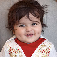Baby dressed in Elvis costume smiles.